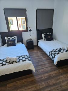 圣巴托洛梅Hotel Masai Mara Resort Gran Canaria的铺有木地板的客房内的两张床