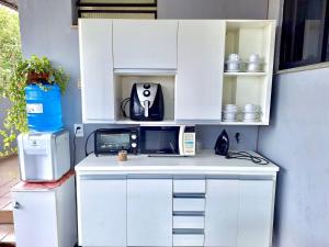 坎普斯戈伊塔卡济斯Quitinete Aconchegante Prq Pelinca的厨房配有白色橱柜和台面上的电器