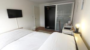 朗伊顿Spacious Room with Parking TV Wi-Fi Desk Kettle的卧室配有白色的床和平面电视。