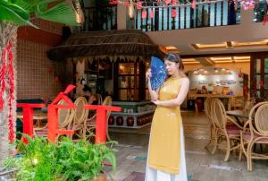 岘港Seahorse Signature Danang Hotel by Haviland的穿着黄色衣服的女子,手持蓝色风扇