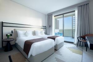 麦纳麦Fraser Suites Al Liwan的酒店客房设有两张床和大窗户。