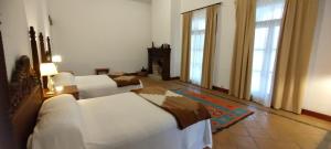卡法亚特Finca El Recreo的一间带2张白色床和2扇窗户的卧室