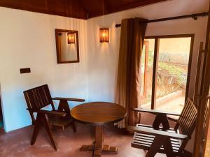 代尼耶耶The Rainforest Hideaway的客房设有桌子、两把椅子和窗户。