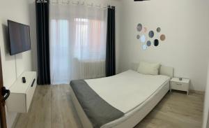 BîrladEnjoy Apartment Barlad的一间白色卧室,配有床和电视