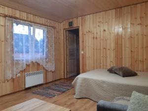 TreimaniTreimani Hoovimaja的一间卧室设有木墙和一张带窗户的床