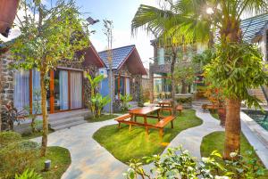 宁平Tam Coc Serenity Hotel & Bungalow的一个带木凳和树木的花园