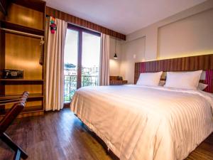 拉巴斯Altus Express Hotel的一间卧室设有一张大床和一个大窗户