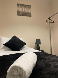 莱斯特Spacious 4-bed House in Leicester的一张带黑白毯子和灯的床