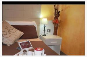菲乌米奇诺萨布丽娜机场酒店的一间卧室配有一张床和一张带台灯的桌子