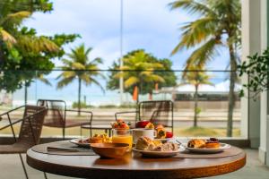 里约热内卢Lifestyle Laghetto Collection的一张桌子,上面放着盘子,享有海滩美景