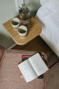 蓬塔德尔加达NINE DOTS Azorean Art Boutique Hotel的一张桌子,上面有两杯,床边有一本书