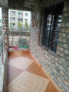 西里古里Areca Holiday Apartment的铺有木地板并拥有砖墙的阳台