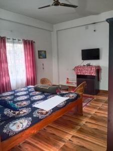西里古里Areca Holiday Apartment的一间卧室配有一张床、一张桌子和一台电视