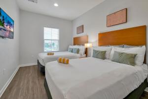 奥兰多Regal Oaks Resort Vacation Townhomes by IDILIQ的白色墙壁客房的两张床
