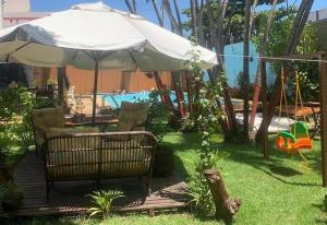瓜拉派瑞Espaço Hale Kai的一个带遮阳伞和椅子的庭院和一个游泳池