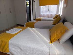 ArchidonaHotel Yurak的配有黄色枕头的客房内的两张床