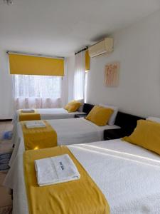 ArchidonaHotel Yurak的酒店客房,设有三张带黄床单的床