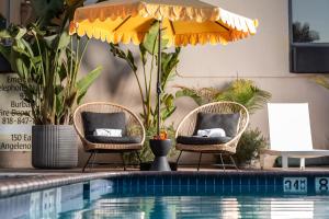 伯班克Hotel Burbank的游泳池旁的两把椅子和一把遮阳伞