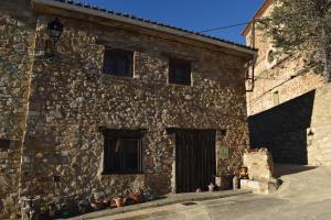 特连特Casa rural La Endrina的一座石头建筑,设有两扇窗户和一扇门