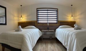 利纳雷斯维多利亚塞德酒店的一间卧室设有两张带白色床单的床和窗户。