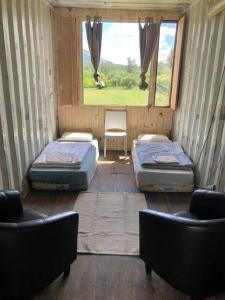 皮里亚波利斯Glamping in Uruguay’s hidden gem的客房设有两张床、两把椅子和窗户。