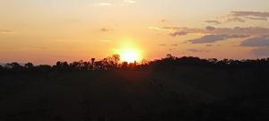 康塞高伊比蒂波卡IbitiAnJo - Suítes的一片在前方树木繁茂的田野上的日落