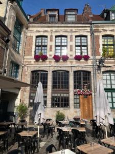 里尔Chambre privée Place aux oignons的大楼前的户外庭院配有桌子和遮阳伞