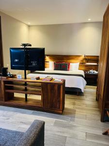 瓦哈卡市埃卡莱洪精品酒店的一间卧室配有一张床和一张书桌及电视