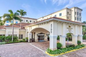 棕榈滩花园希尔顿棕榈滩花园惠庭套房酒店的一座拥有大门和棕榈树的酒店大楼