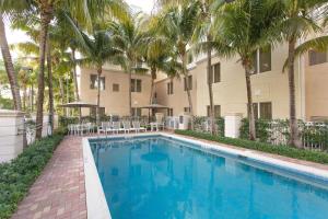 棕榈滩花园希尔顿棕榈滩花园惠庭套房酒店的棕榈树建筑前的游泳池