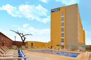 坦皮科City Express by Marriott Tampico Altamira的酒店游泳池设有椅子,大楼
