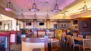 弗林特Gateway Hotel & Convention Center Grand Blanc Flint Airport Michigan的一间带桌椅的餐厅和一间酒吧