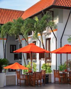 库塔HARRIS Hotel Kuta Tuban Bali的一组桌子,上面有橙色伞,放在大楼前