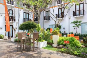 库塔HARRIS Hotel Kuta Tuban Bali的一座花园,位于一座带椅子和植物的建筑前