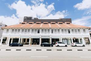 新加坡Santa Grand Hotel East Coast a NuVe Group Collection的一座白色的建筑,前面有汽车停放