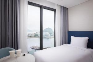 釜山Citadines Connect Hari Busan的酒店客房设有一张床和一个大窗户