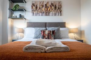 卡迪夫2-bedroom Cardiff Bay apartment Wi-Fi, Parking的一间卧室配有一张带毯子和两盏灯的床。