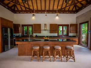 甲米镇Baan Pinya Balinese Style Pool Villa的一个带木柜的厨房和一个带酒吧凳的岛屿