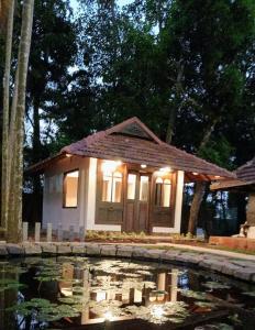 阿勒皮Shantitheeram Ayurveda Lakeside Heritage Resort的池塘前灯的小房子