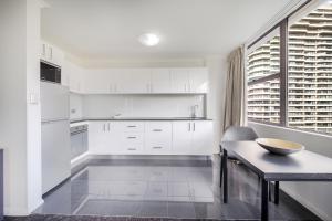 悉尼Oaks Sydney Hyde Park Suites的厨房配有白色橱柜、桌子和窗户。
