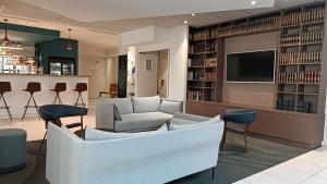 里尔快捷假日里尔中央酒店的一个带沙发和椅子的图书馆和一台电视