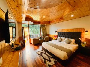 马拉里Himalayan Riverside Resort, Manali的一间带一张大床的卧室,位于一个拥有木制天花板的房间