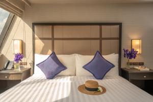 曼谷曼谷素坤逸大道酒店的床上的帽子,带紫色枕头