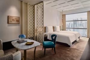 曼谷曼谷瑰丽酒店的酒店客房配有床、桌子和沙发。