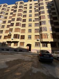 撒马尔罕Уютная квартира в центре города的一座大型建筑,前面有停车位