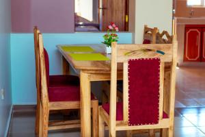 纳纽基Balozi Luxury Homes的一张木桌和椅子,配有红色靠垫