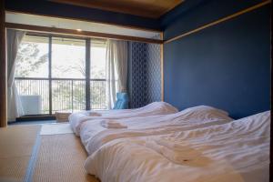 伊东ISOLA Izukogen的一间卧室设有两张白色的床和窗户