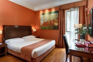佛罗伦萨亚德里亚海大酒店的配有一张床、一张书桌和一扇窗户的酒店客房