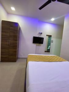 孟买Hotel Blue Wellington - Near Mumbai Airport的一间卧室配有一张床、一个橱柜和一台电视