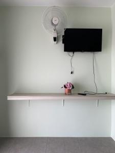 西哈努克Ginger Sihanoukville的客房设有一张桌子、一台电视和一个风扇。